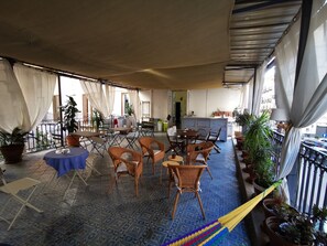 A spacious balcony with wicker furniture, potted plants, and a blue table. - Artisan Maison (Palermo)