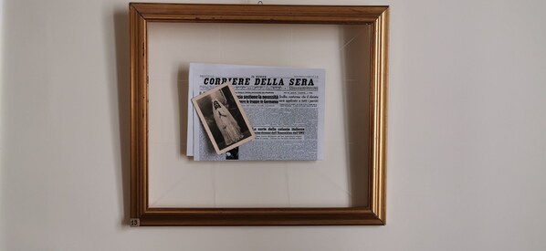 Un artículo de periódico enmarcado con el título 'CORVERE DELLA SERA' y una pequeña fotografía en la parte superior.