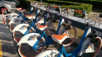 A row of bicycles with orange seats and white frames, parked in a designated area.
