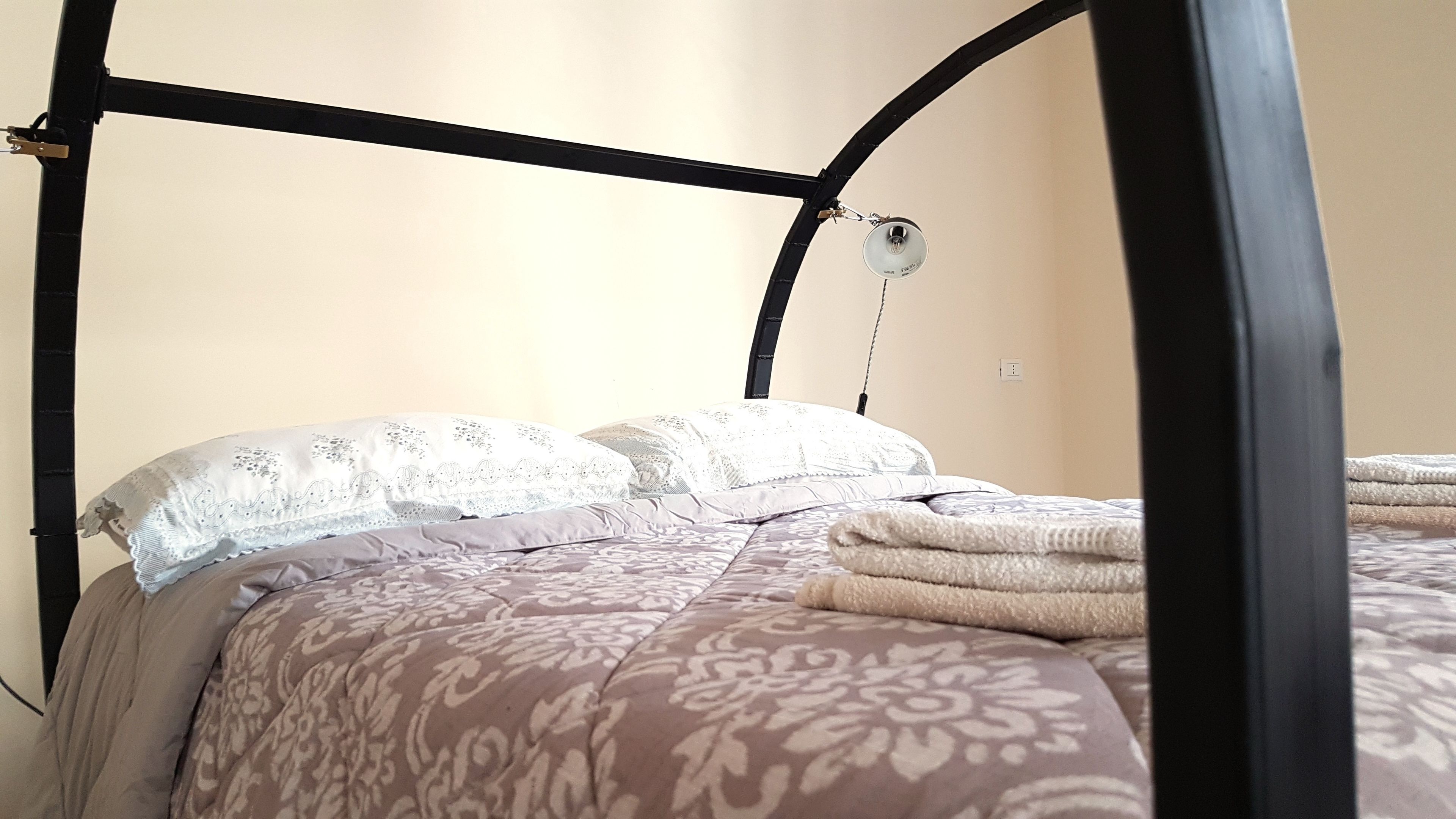 Een bed met hemel, beddengoed met patroon en een bedlampje.