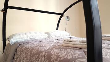 Een bed met hemel, beddengoed met patroon en een bedlampje.