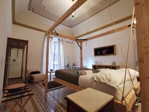 A room with a bed, a small table, a chair, a window with curtains, and a painting on the wall. - Artisan Maison (Palermo)