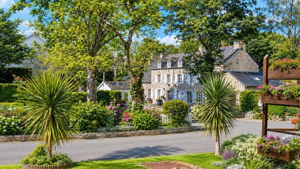 A stone building with a garden in front, a paved road, and a wooden fence. - Camping du Manoir de Penn ar Ster (La Foret-Fouesnant)