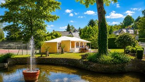 A house with a garden, a pond with a fountain, and a tennis court. - Camping du Manoir de Penn ar Ster (La Foret-Fouesnant)
