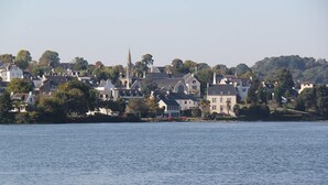 A coastal town with historic buildings, a prominent church spire, and a calm waterfront. - Camping du Manoir de Penn ar Ster (La Foret-Fouesnant)