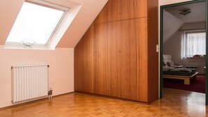 Una habitación con techo inclinado, un armario de madera, un radiador y una ventana.