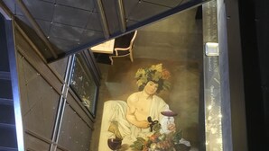A staircase with a mural of a classical figure holding a bowl and fruits.