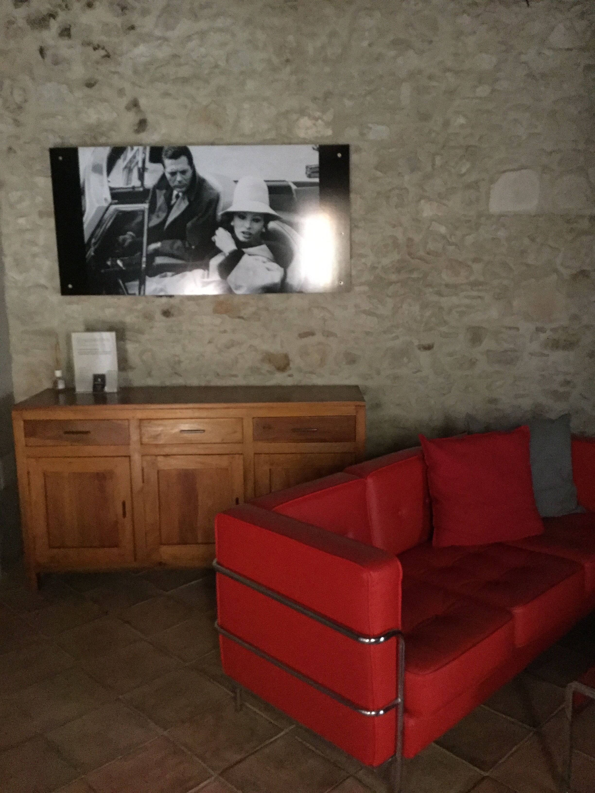 A room with a red sofa, a wooden cabinet, and a framed picture on the wall.