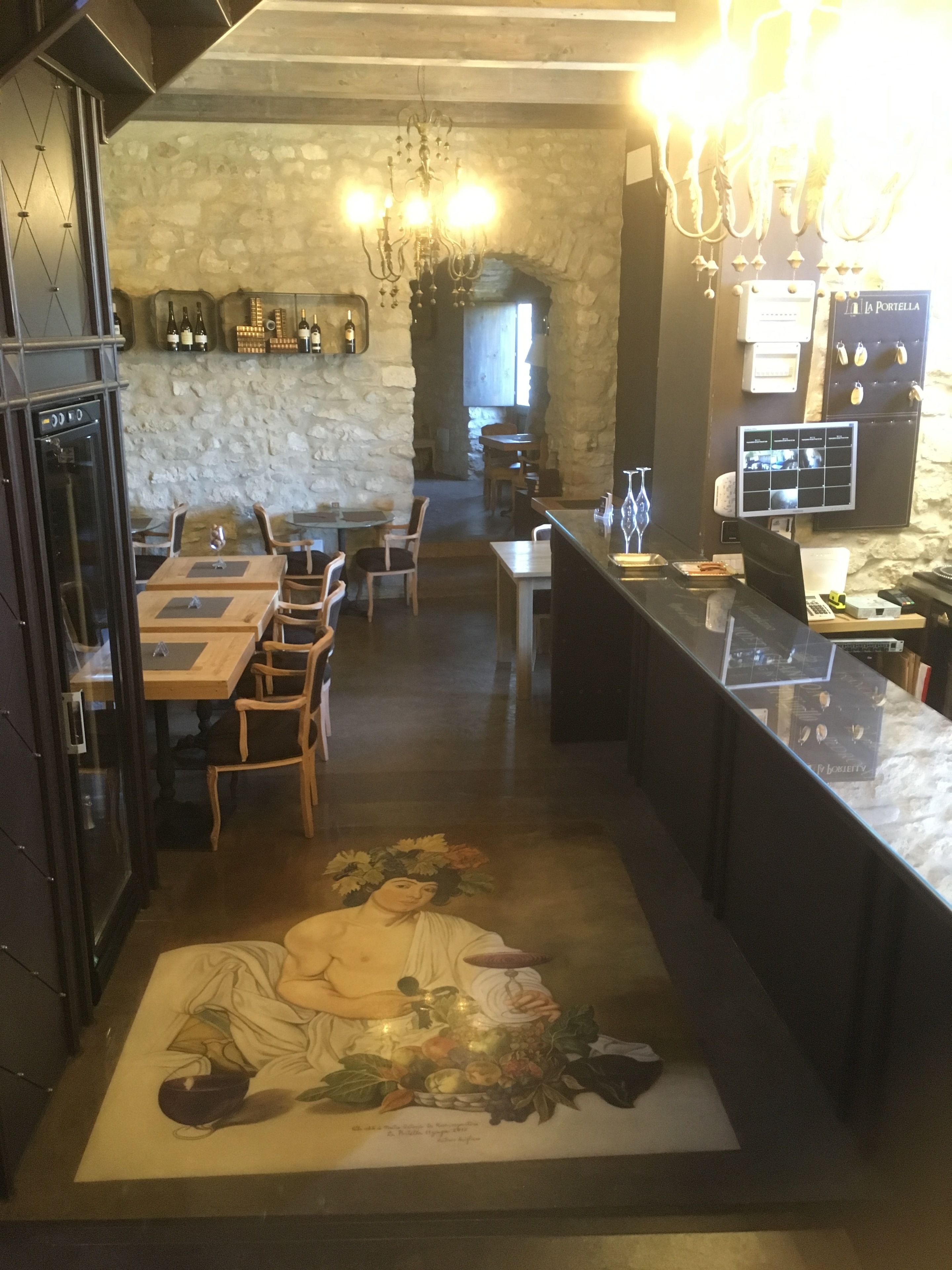 Un restaurant avec un mur en pierre, des tables en bois et un lustre.