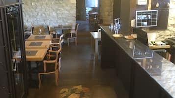 Ein Restaurant mit einer Steinsäule, Holztischen und einer Kristallleuchter.