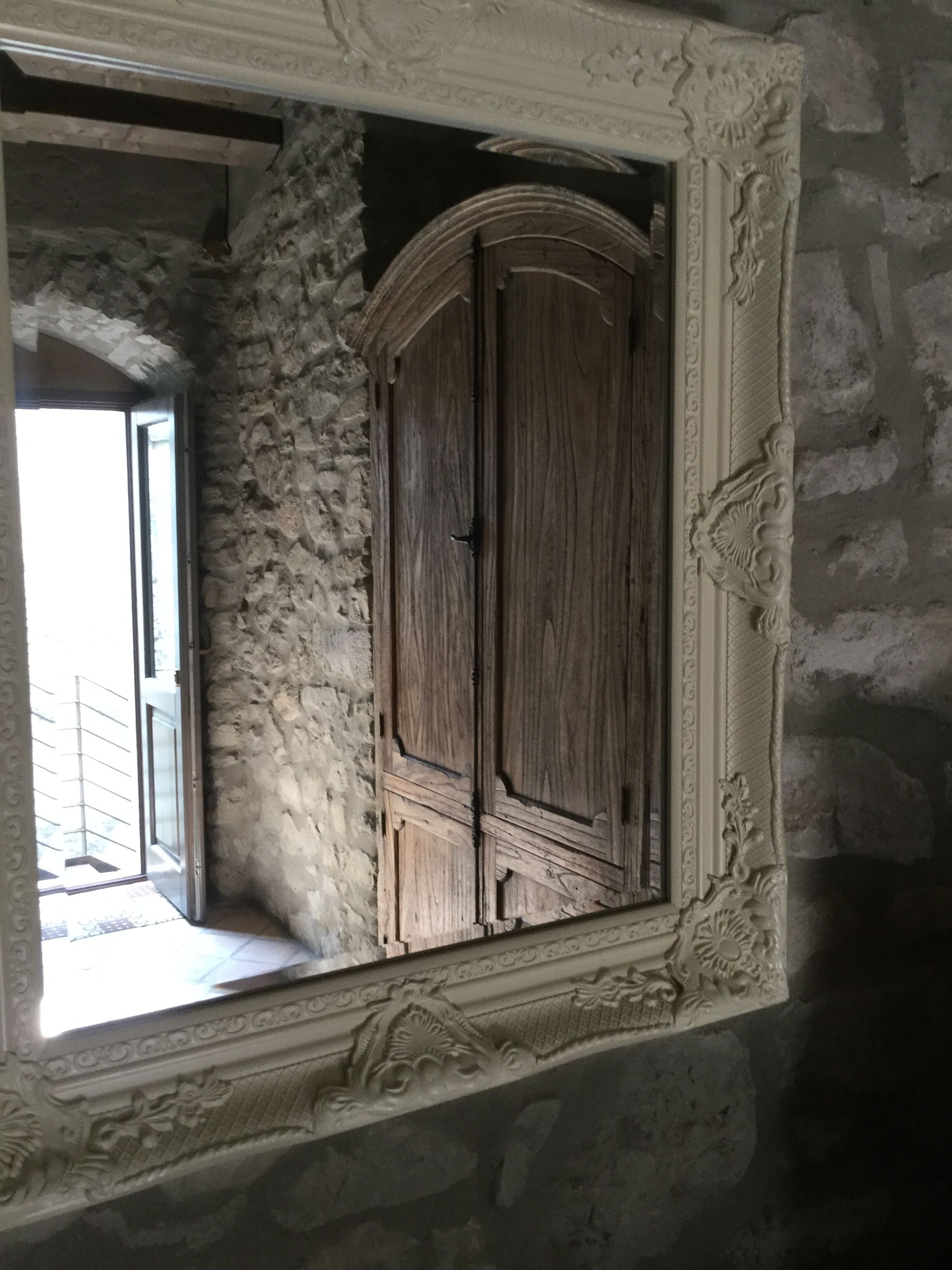 Una habitación con pared de piedra, un armario de madera y un balcón con ventana.