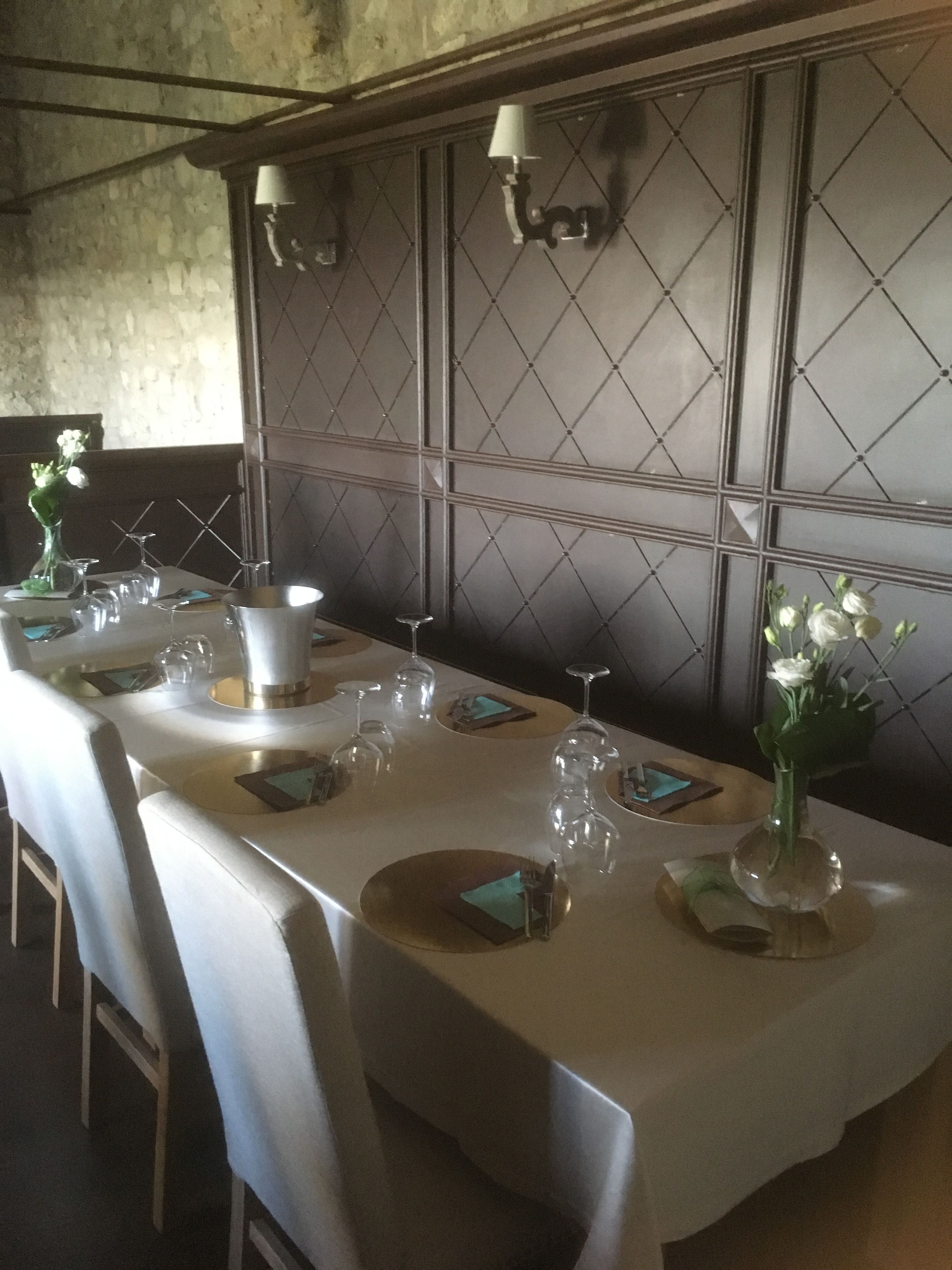 A long dining table set with white tablecloths, plates, cutlery, and wine glasses.