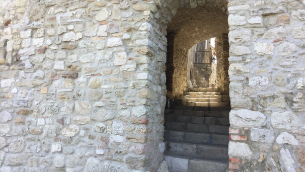 A stone staircase leading to an arched doorway, surrounded by rough stone walls.
