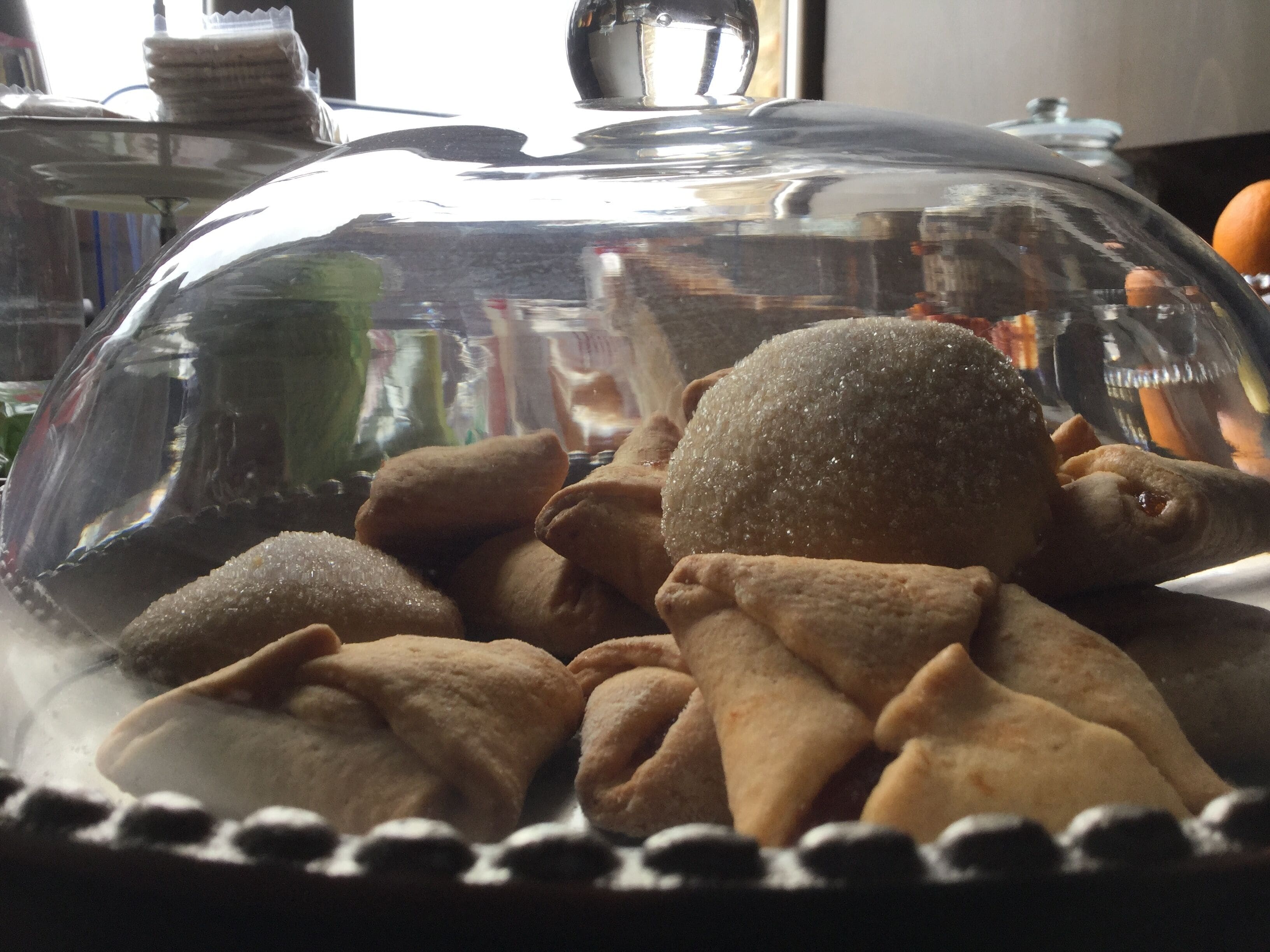Une vitrine en verre contenant diverses pâtisseries, dotée d’une surface réfléchissante et d’un bord décoratif.