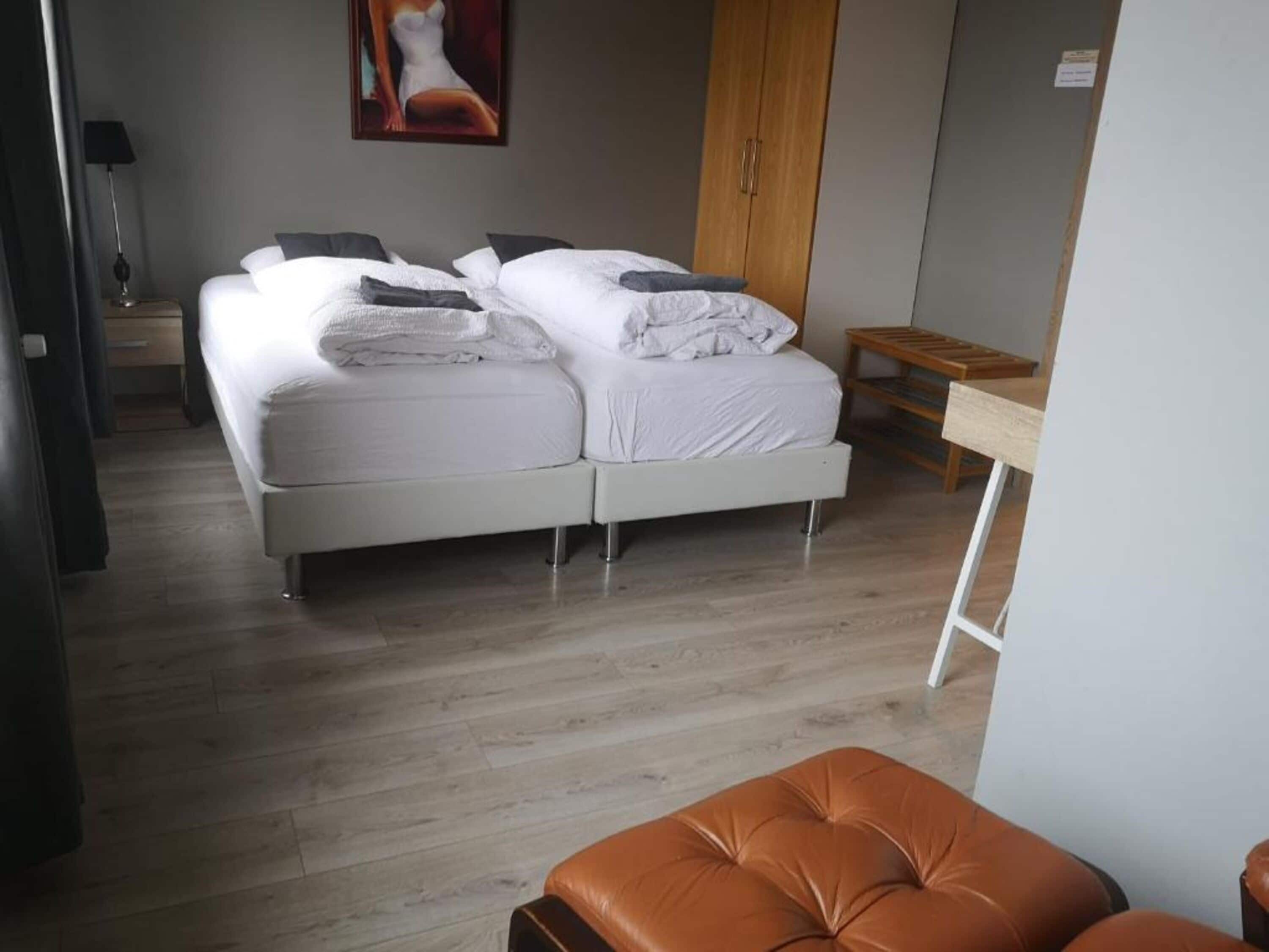 Une chambre moderne avec un lit double, un banc en bois et un tableau accroché au mur.