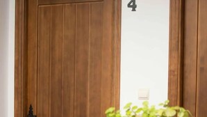 Une porte en bois sur laquelle figure le chiffre « 4 », une petite plante au premier plan et une balustrade noire.