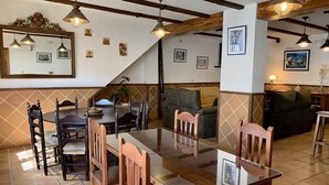Un espace repas comprenant une table et des chaises en bois, un canapé et un escalier menant à un autre niveau.