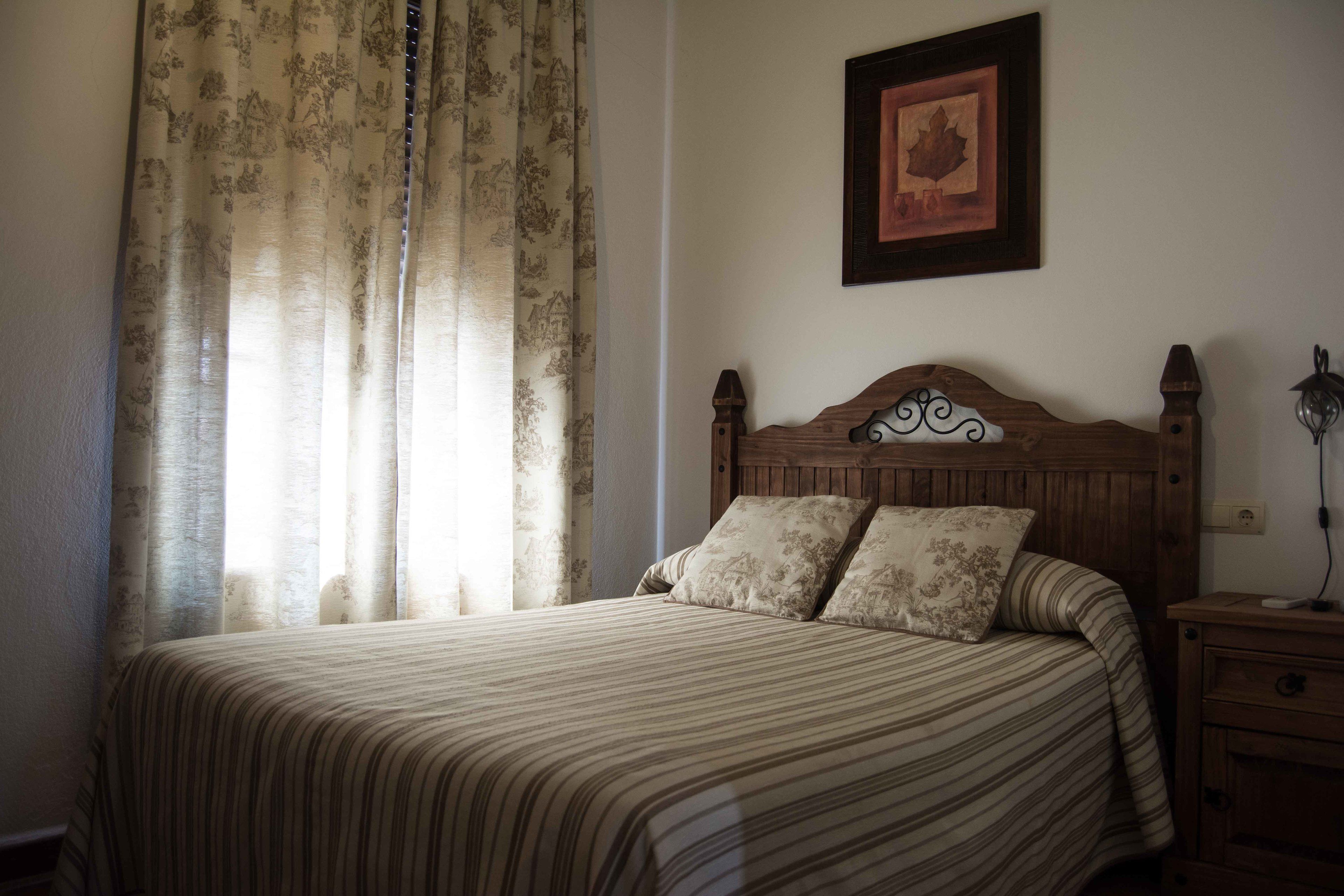 A bedroom with a wooden headboard, a bed with striped bedding, and a nightstand with a lamp.