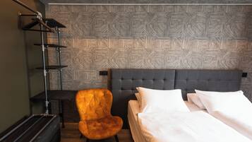 Una habitación de hotel con una cama, una silla, un escritorio y una pared con un diseño geométrico.