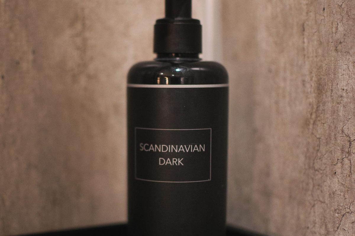 Una botella negra etiquetada 'Scandinavian Dark Hair & Body Gel' sobre una bandeja negra.