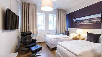 A hotel room with two beds, a desk, a chair, a TV, and a painting on the wall.