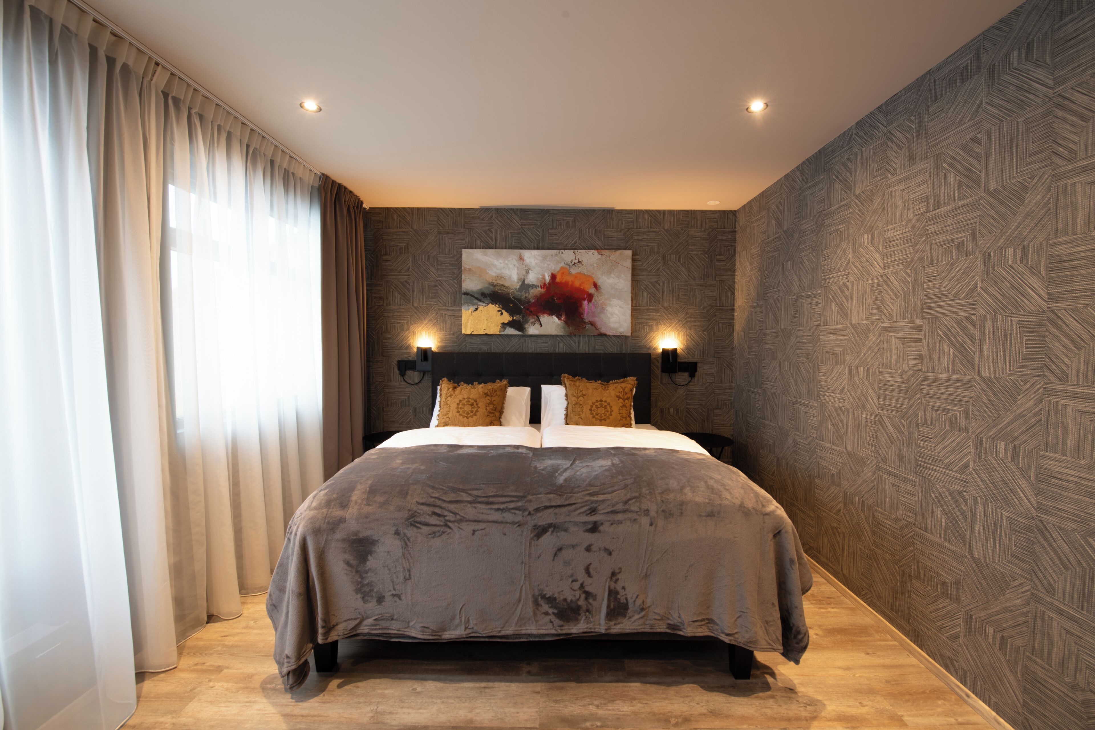 A modern bedroom with a large bed, a painting on the wall, and a patterned wallpaper.