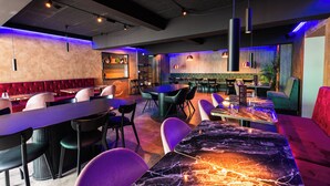 Un interior de restaurante moderno con mesas de mármol, asientos acolchados e iluminación ambiental.