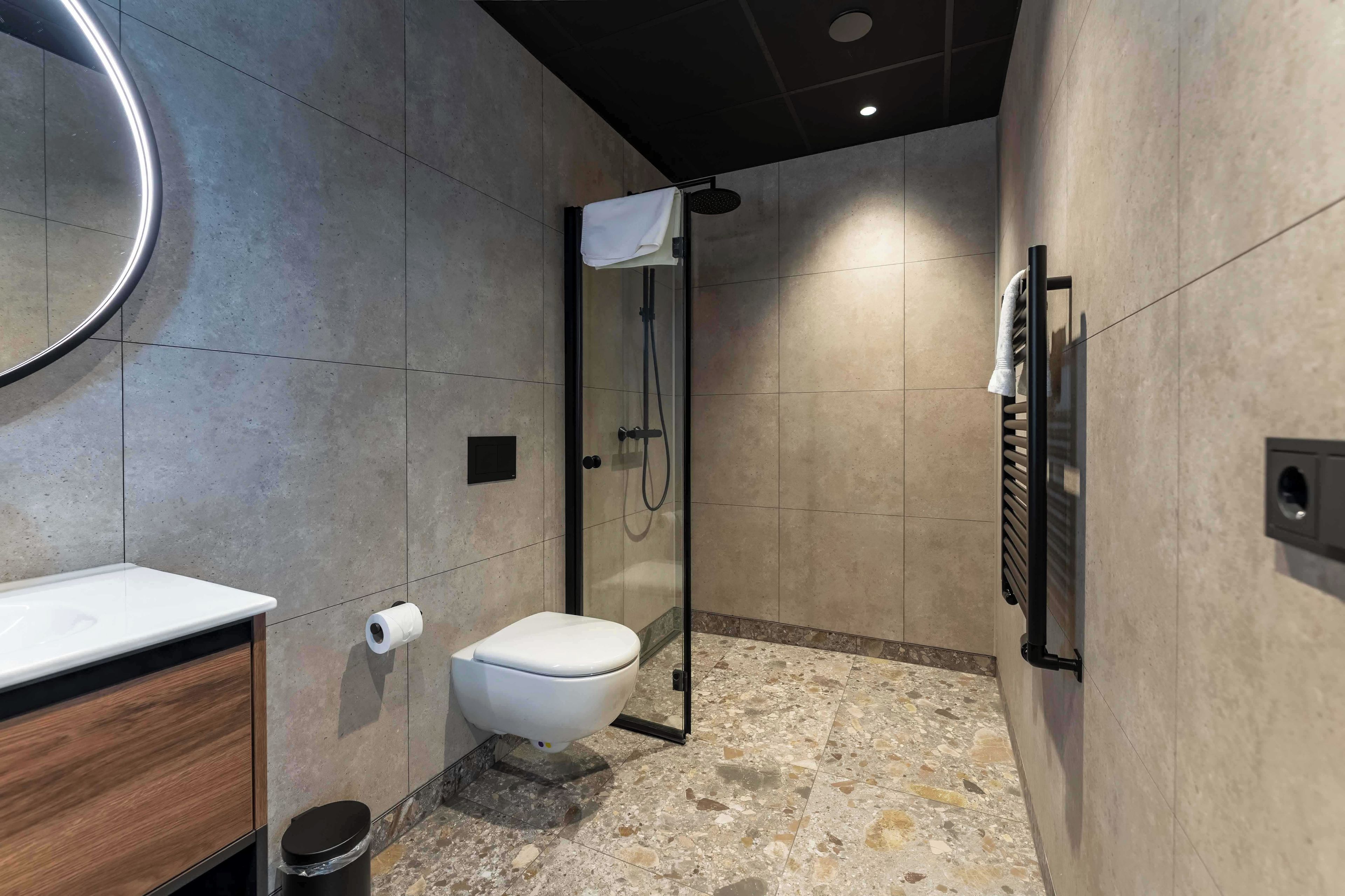 A modern bathroom with a toilet, shower, and a mirror.