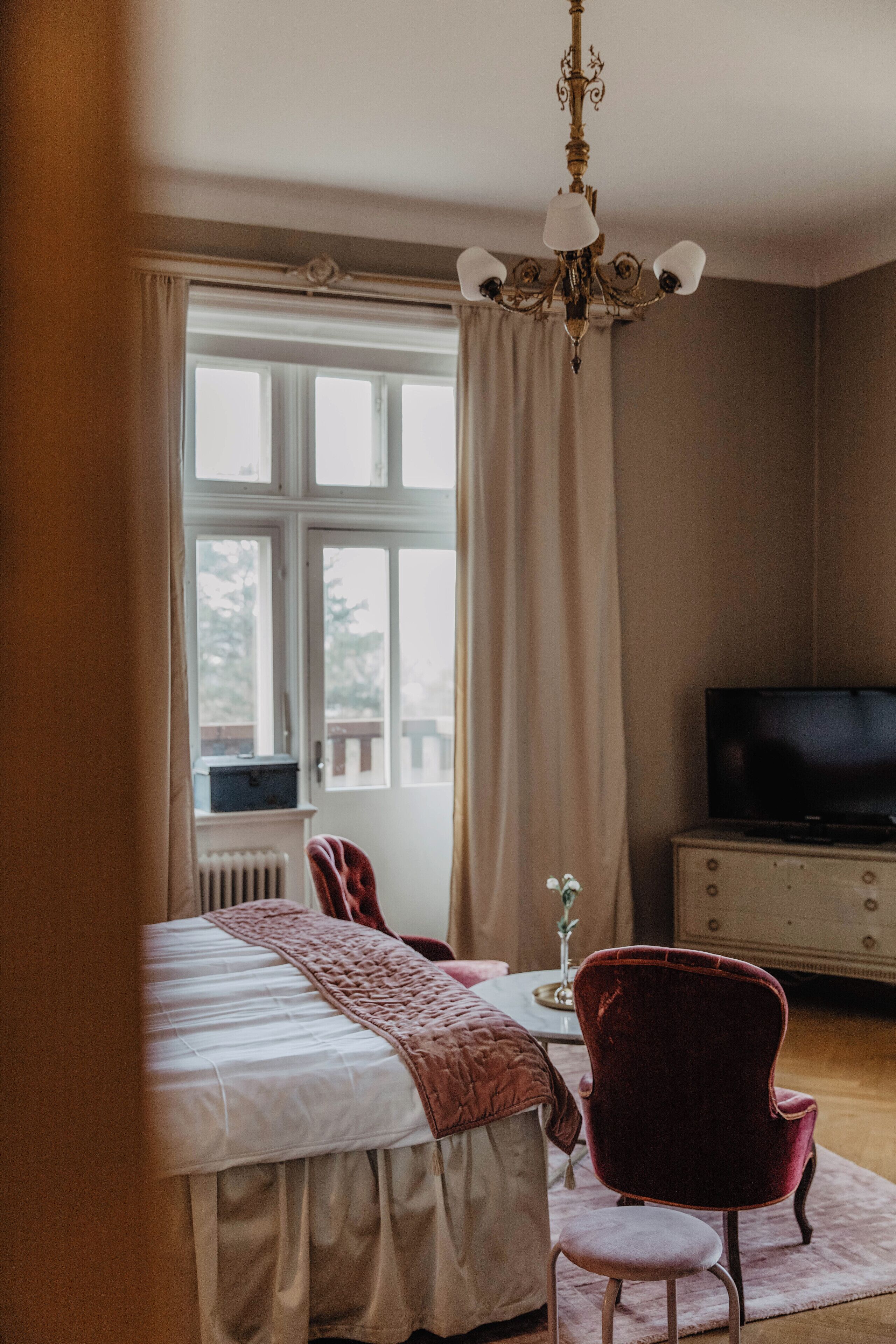 Une chambre à coucher avec un lit, une chaise, une commode et un téléviseur.