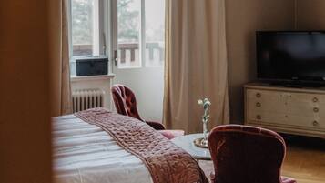 A bedroom with a bed, a chair, a dresser, and a television.