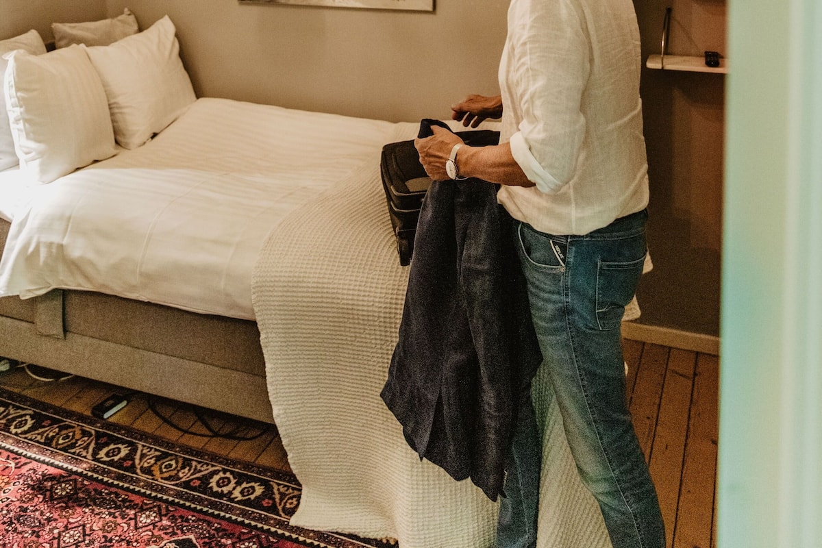 Une chambre à coucher avec un lit, un lustre, un tableau et une étagère ornée d’objets décoratifs.