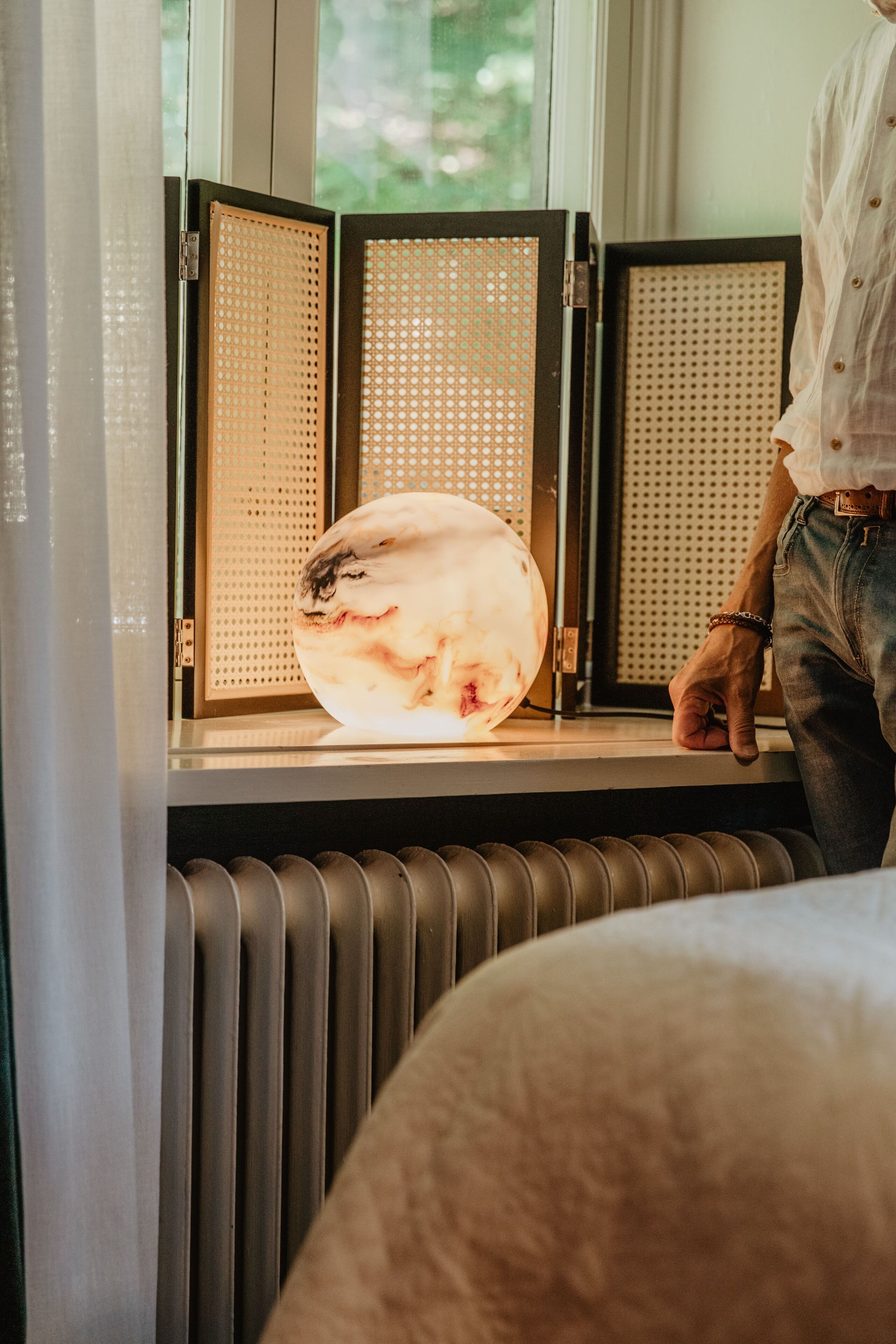 Eine Person steht an einem Fenster mit einer dekorativen Leuchte.