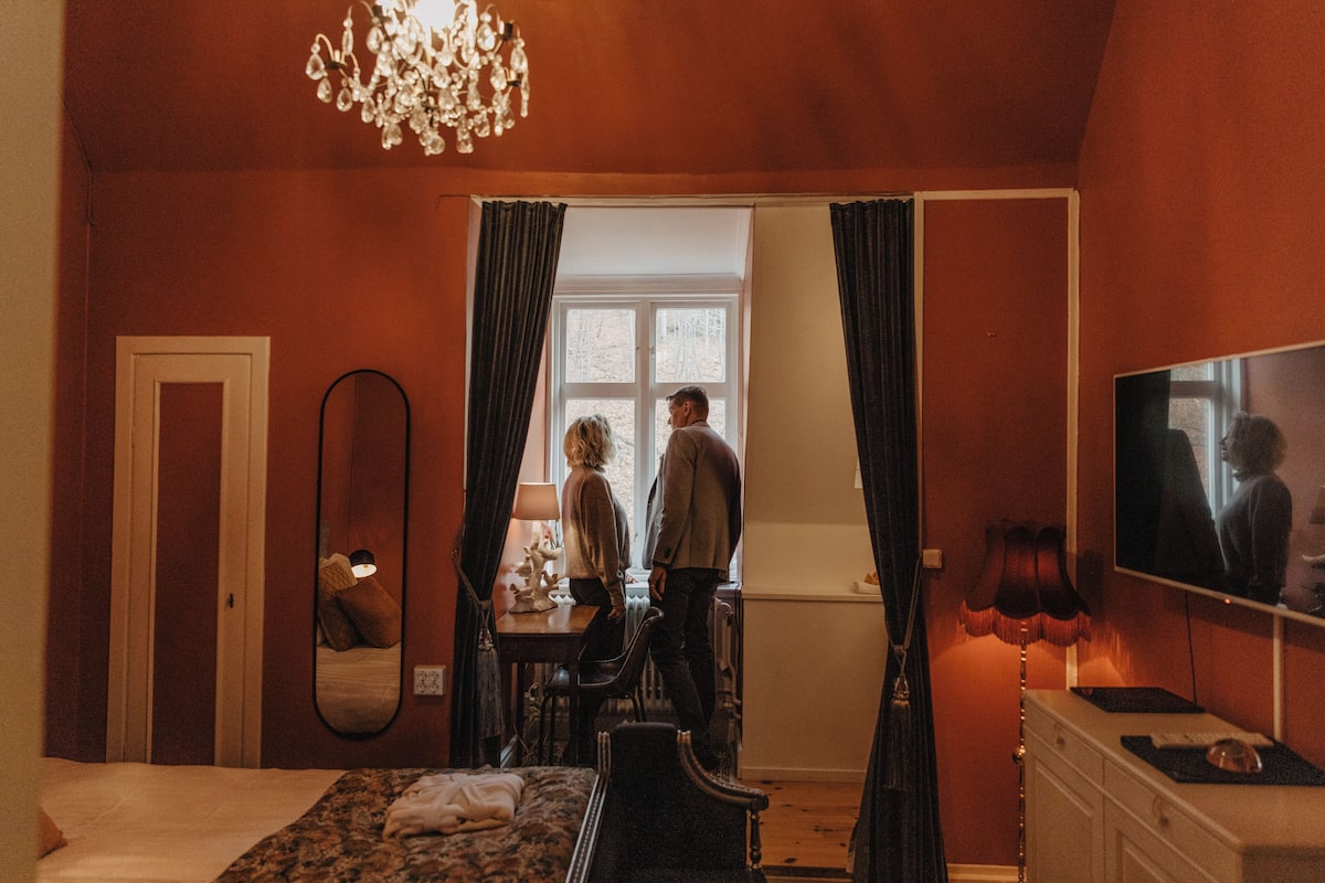 Une chambre d’hôtel équipée d’un lit, d’un bureau, d’une chaise, d’une télévision et d’une fenêtre avec des rideaux.