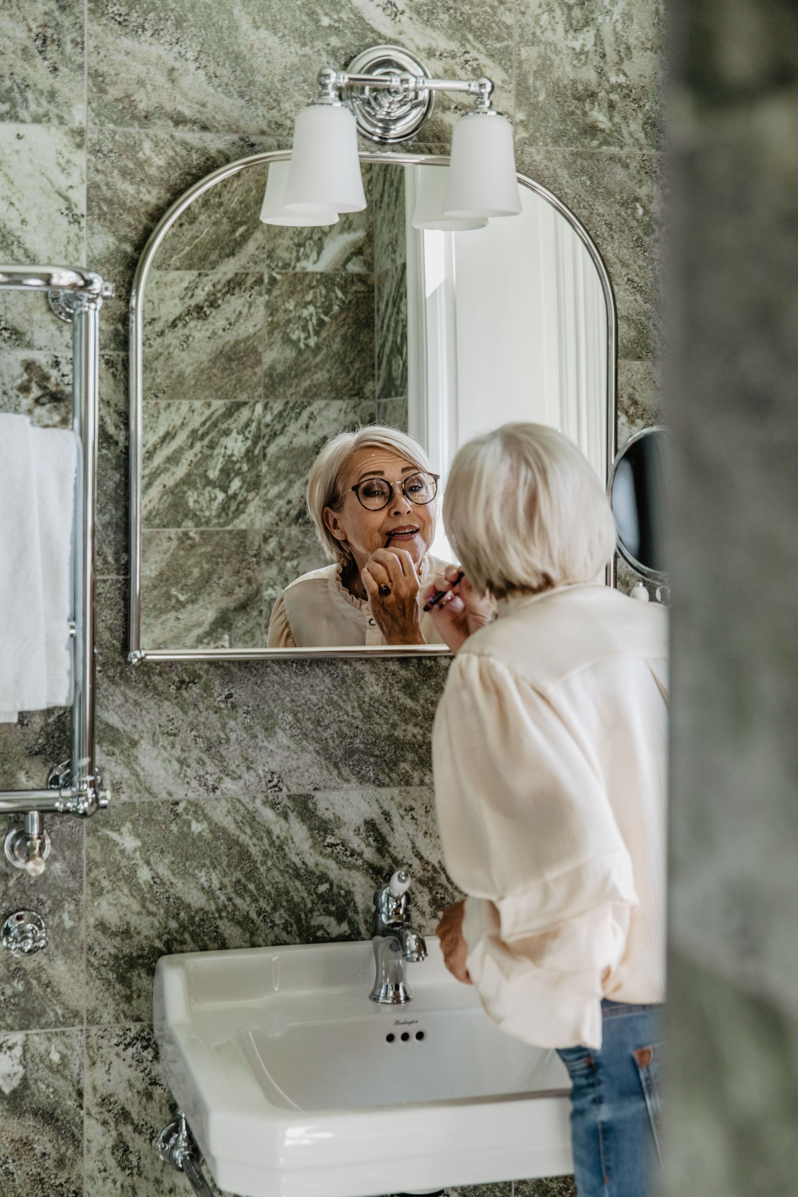 Une salle de bain avec un mur en marbre, un lavabo et un miroir avec éclairage intégré.