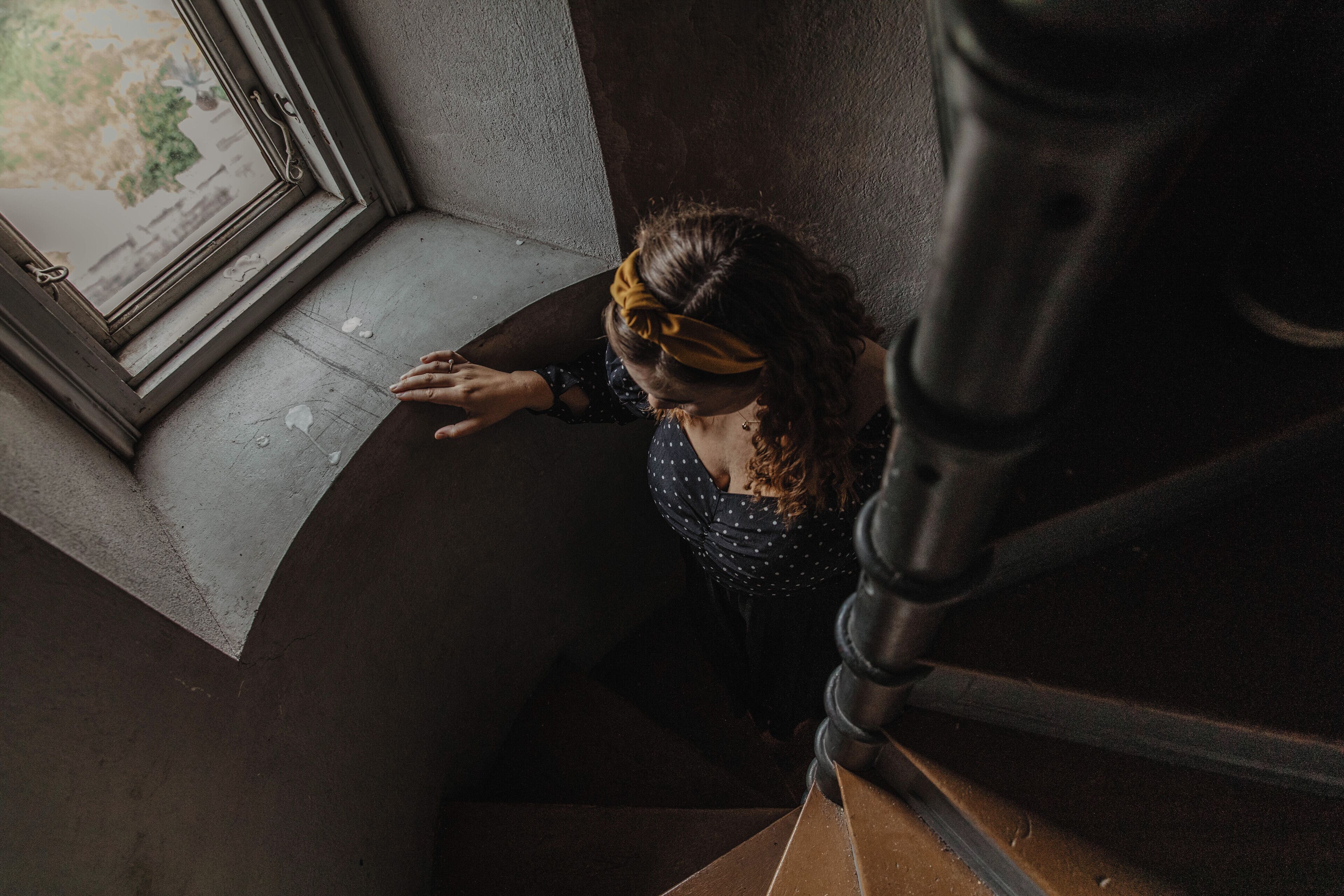 A person descending a staircase with a window at the top.