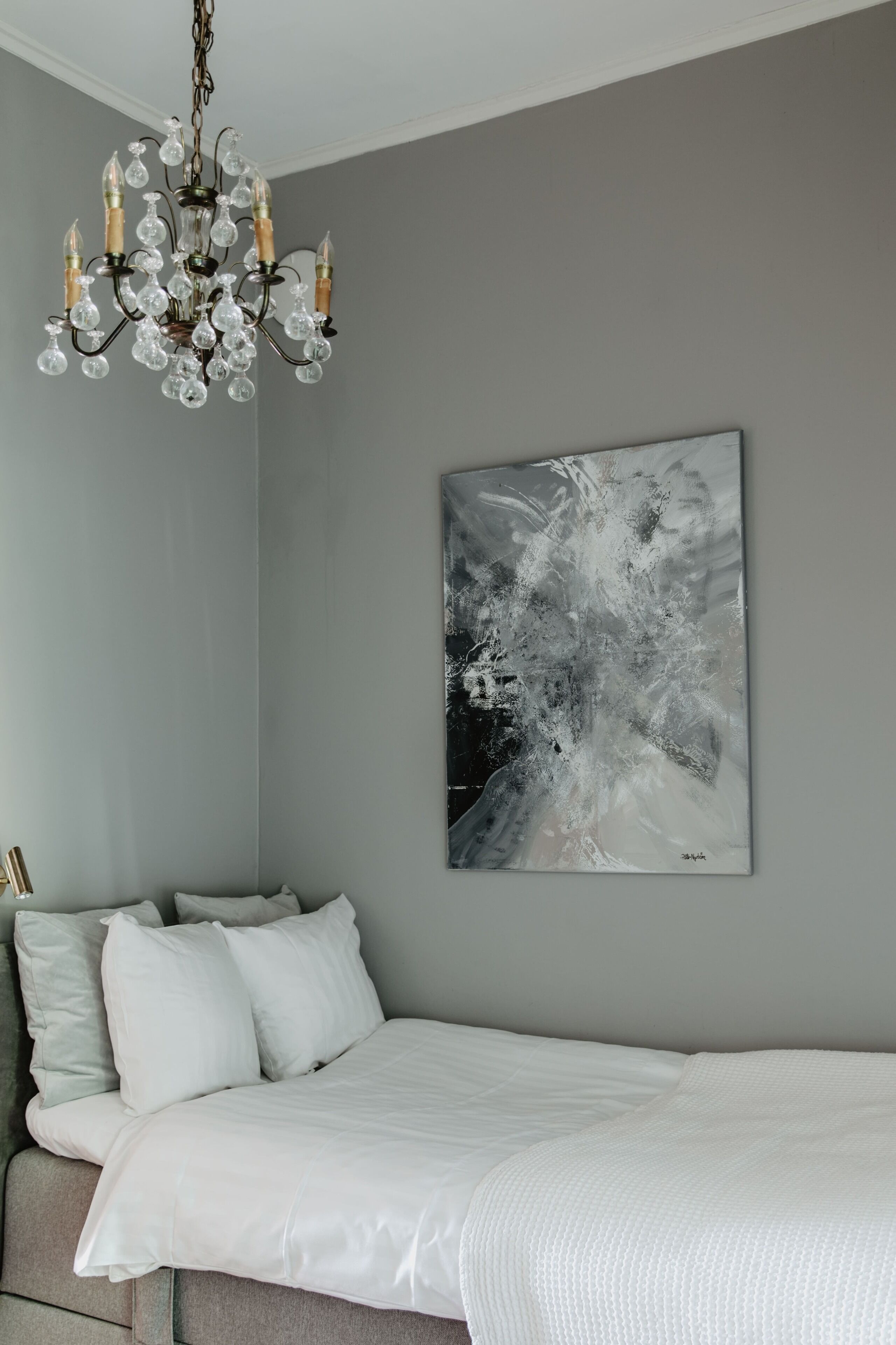Une chambre à coucher avec un lit, un lustre et une œuvre d’art murale.