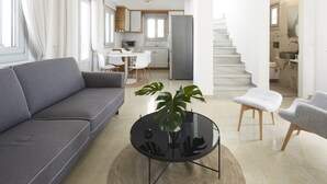 Una sala de estar moderna con un sofá gris, una mesa de centro redonda negra y una planta en maceta.