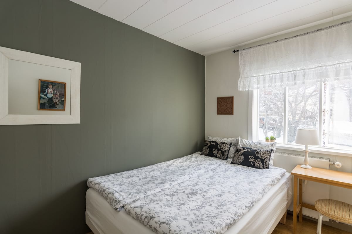 A bedroom with a bed, a desk, and a window.