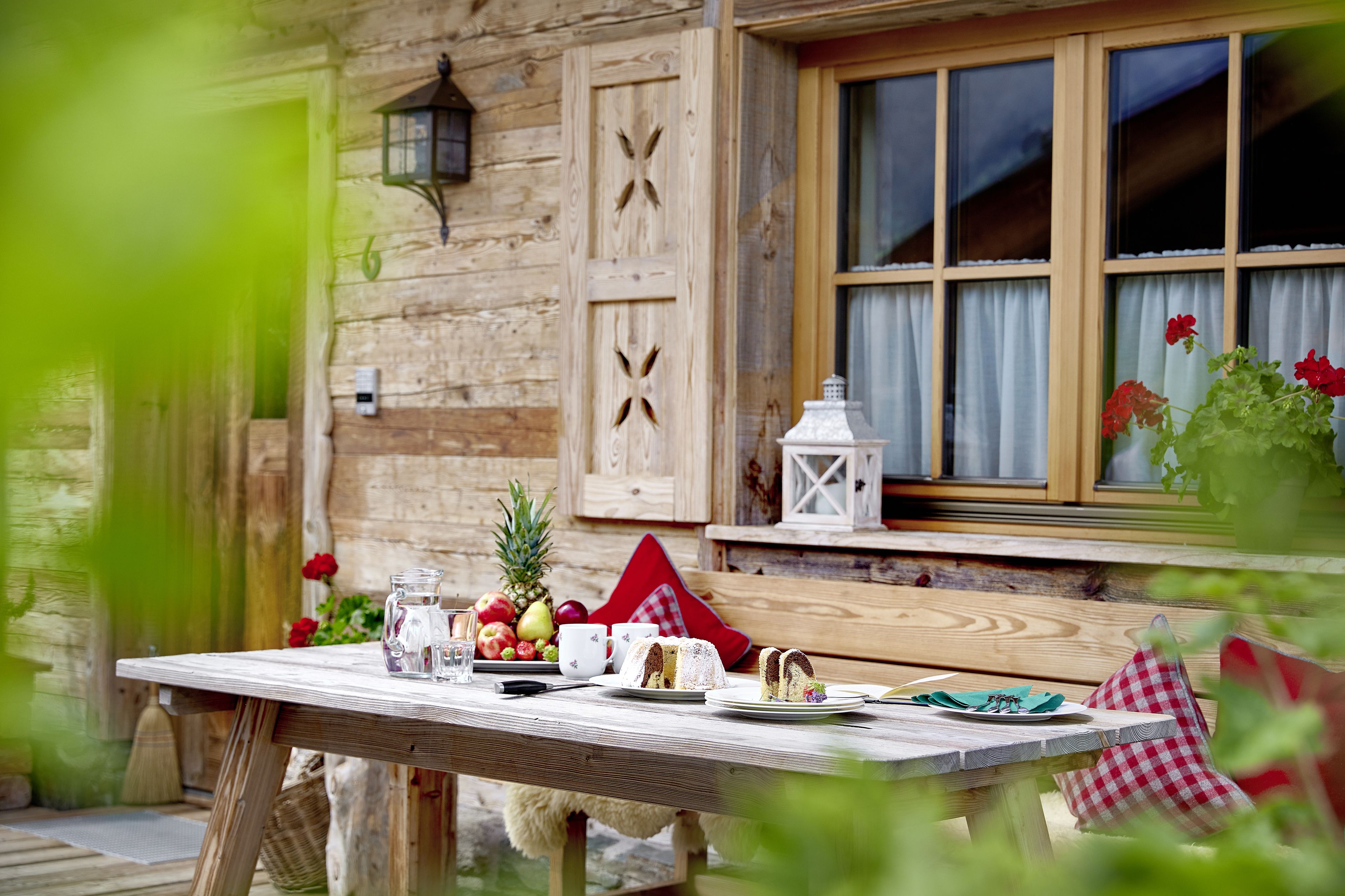 A wooden table set with food and drinks, a window with curtains, and a rustic wooden wall.