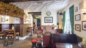 Un acogedor interior de restaurante con mobiliario de madera, una chimenea de ladrillo y un tapete de cuero de vaca.