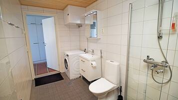 A modern bathroom with a washing machine, a toilet, and a shower.