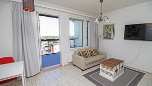 Una sala de estar moderna con un sofá, una mesa de centro, un televisor y vistas al exterior.