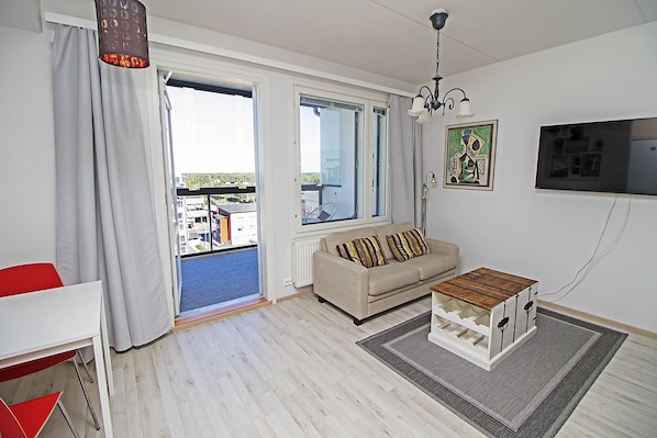 Una sala de estar moderna con un sofá, una mesa de centro, un televisor y vistas al exterior.