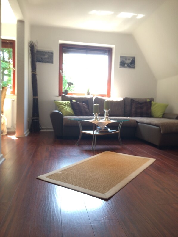 A living room with a sofa, a coffee table, and a rug. - Zimmervermietung Arp 17 (Itzehoe)