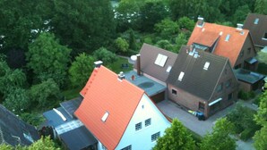 A residential area with houses featuring red and brown roofs, surrounded by dense green trees.