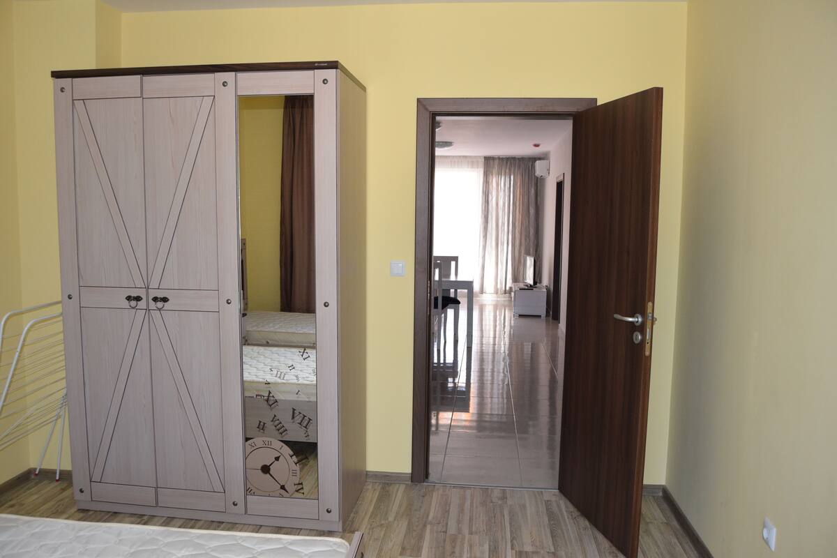 Een slaapkamer met een kledingkast, een bed en een deur naar een andere kamer.