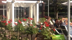 Ein Gartenbereich mit Sitzgelegenheiten und einer Pergola mit weißen Vorhängen.
