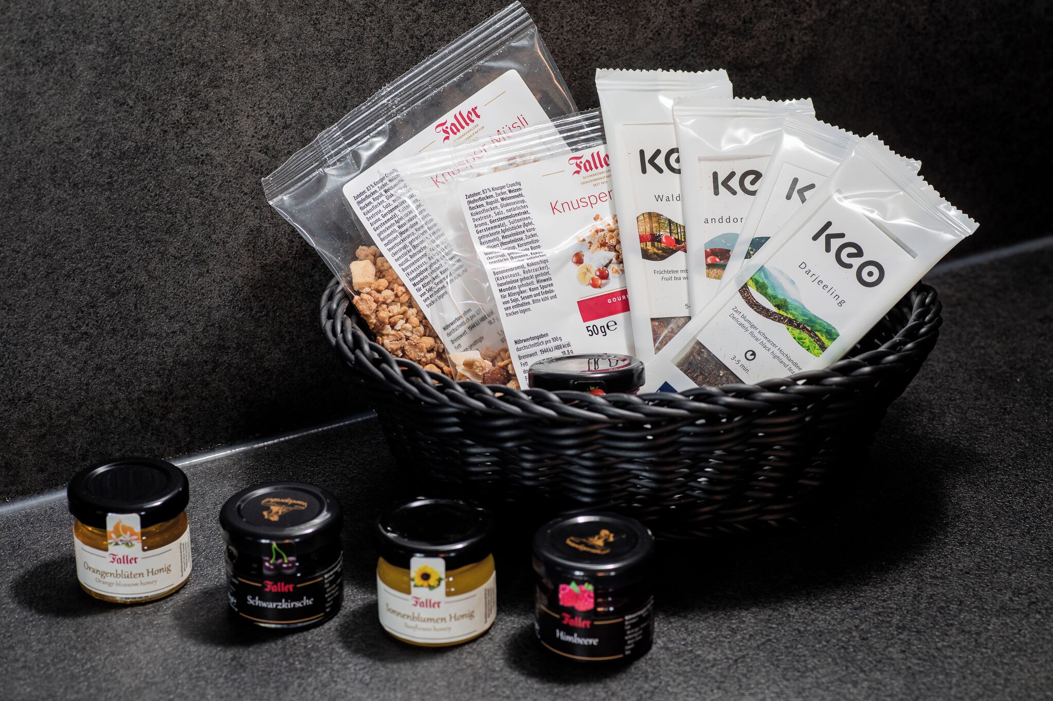Un panier contenant divers produits alimentaires, notamment des en-cas emballés et des pots de confitures.