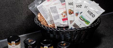 Un panier contenant divers produits alimentaires, notamment des en-cas emballés et des pots de confitures.