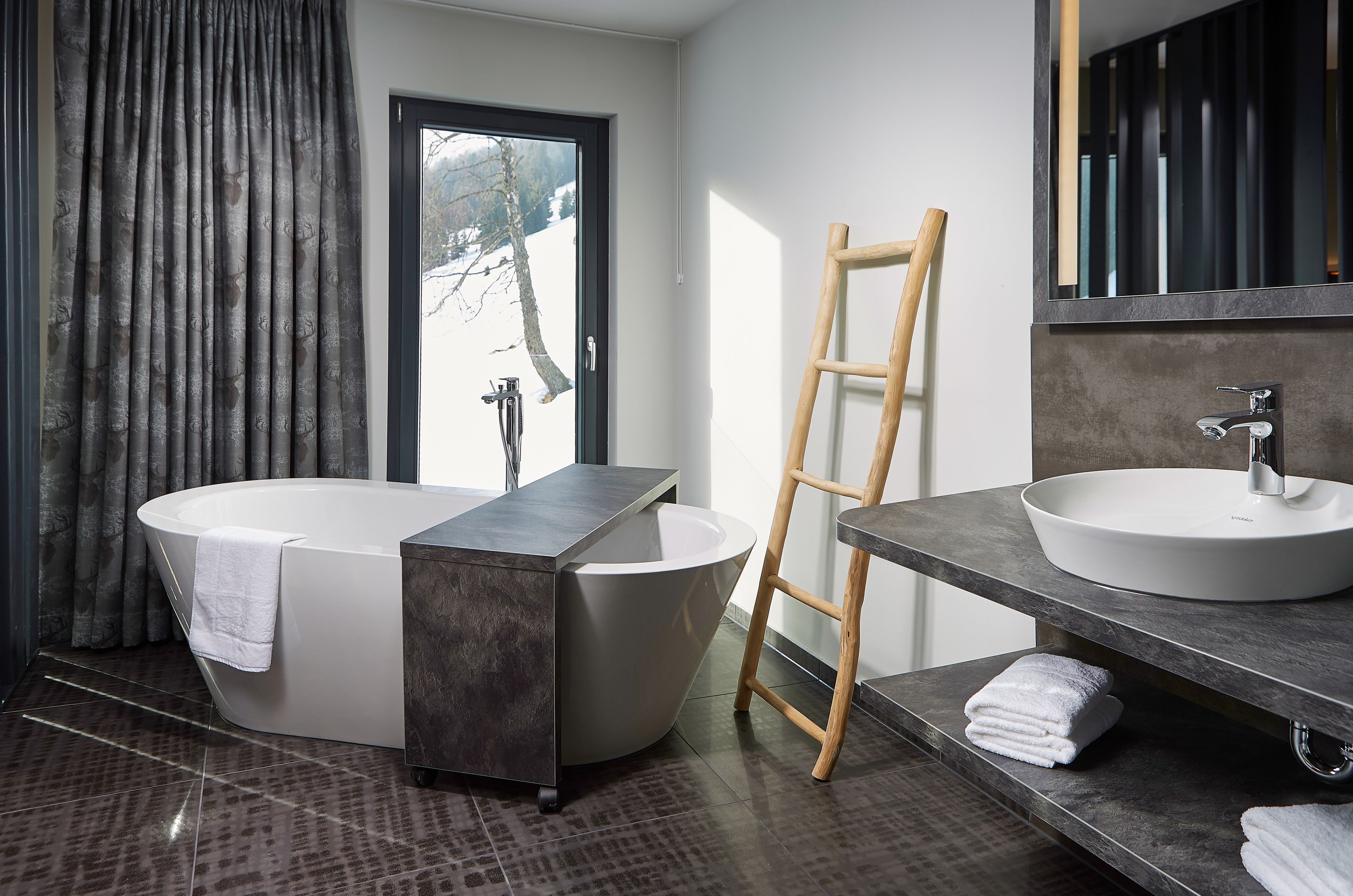A modern bathroom with a freestanding bathtub, a vanity with a sink, and a large mirror.